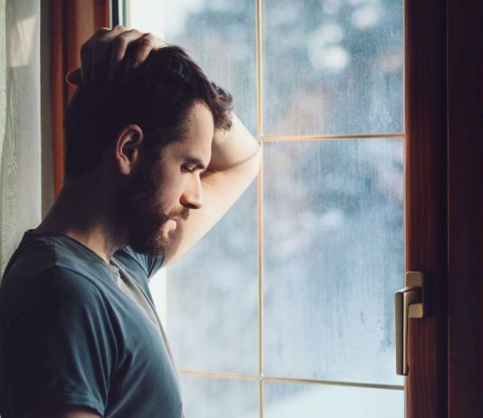 homem-com-sintomas-de-depressão-olhando-pela-janela