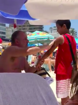 homemnapratica.com - Homem passa protector solar em menino que vendia bala na praia