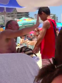 homemnapratica.com - Homem passa protector solar em menino que vendia bala na praia